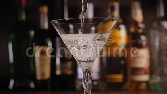 马丁尼被倒进酒吧里的玻璃杯里杯底是模糊的瓶子视频的预览图