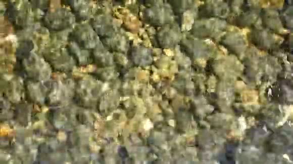 干净的圆形石头在水晶水中清晰可见上面是干净的水晶水和灰色的黄色卵石视频的预览图
