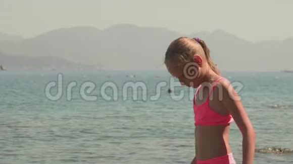 可爱的女孩看着海水在夏天思考视频的预览图