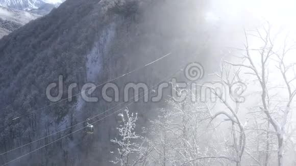 滑雪电梯在低地的雪山森林上移动载着滑雪者和滑雪者到雪坡的滑雪缆车视频的预览图