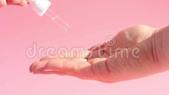 滋润血清滴管和粉红色背景上的女性手视频的预览图