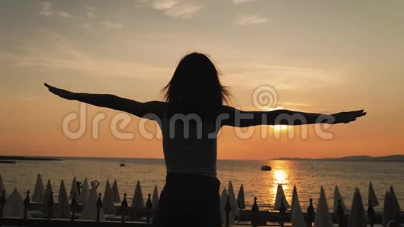 年轻女孩日落时在海洋上玩耍的剪影暑假积极情绪视频的预览图