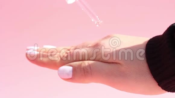 滋润血清滴管和女性手粉色背景概念手护理视频的预览图