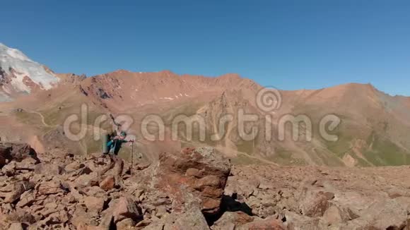 一位旅行者爬上一块大石头来观赏周围的山景视频的预览图