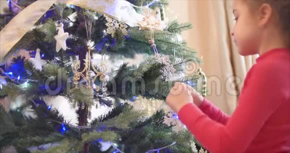 小女孩或小孩把新年玩具挂在圣诞树上装饰圣诞树圣诞节视频的预览图
