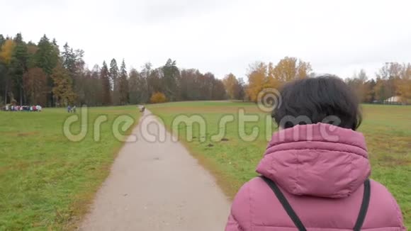 白种人中年妇女在露天公园的道路上行走镜头移动视频的预览图
