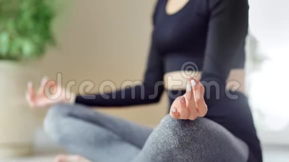 特写女性双手练习瑜伽双腿坐在莲花位置侧视视频的预览图
