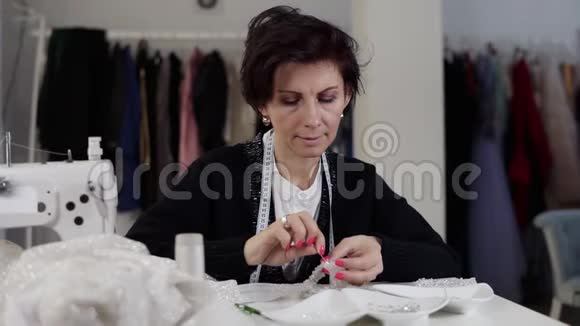 一个女裁缝用婚纱做细节的肖像持有针线和装饰独家视频的预览图