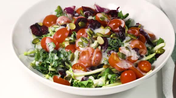 蔬菜沙拉的绿叶混合西红柿南瓜子干蔓越莓和调料视频的预览图