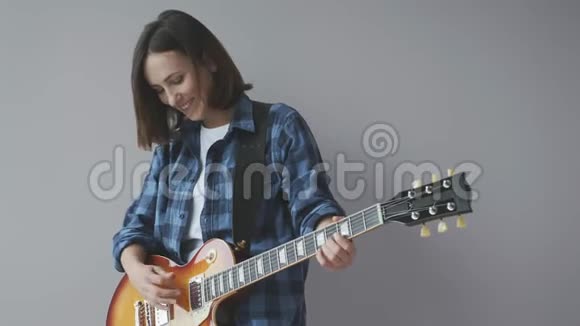 幸福美丽的女人用电吉他演奏摇滚和蓝调歌曲穿着蓝色休闲衬衫微笑和笑摇滚吉他p视频的预览图