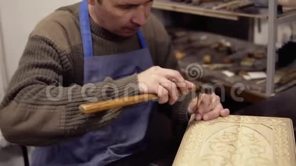 坐在他工作的地方一位工匠在后座上雕刻木制装饰品把一个正在工作的人的录像视频的预览图
