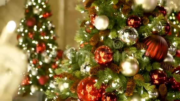 彩色装饰的户外圣诞树在模糊的闪闪发光的仙女背景上有明亮的红色球视频的预览图