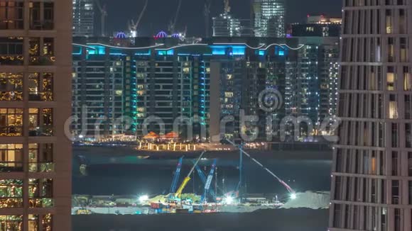 鸟瞰迪拜码头摩天大楼与建筑工地和棕榈朱美拉岛背景夜间时间推移视频的预览图