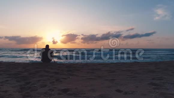 摄影师在海滩上拍摄大海和戏剧性的日出视频的预览图