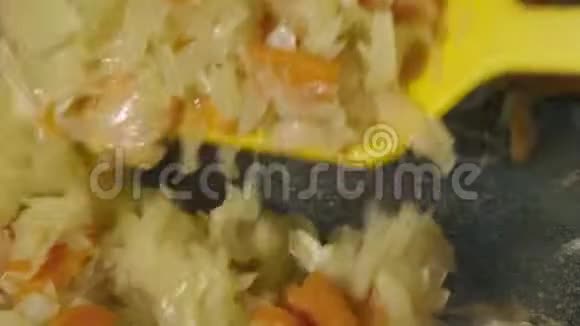 厨师用锅中的锅铲搅动胡萝卜和洋葱并加入植物油视频的预览图