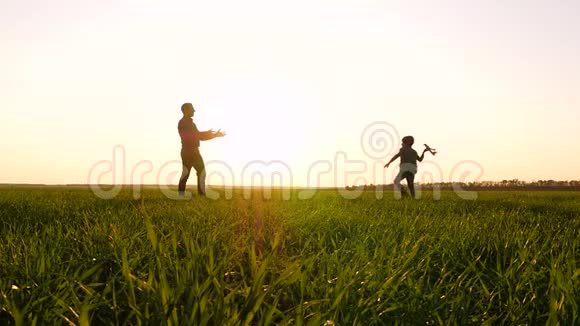 一个小男孩在日落的背景下和他的爸爸玩时发射了一架玩具飞机幸福的概念视频的预览图