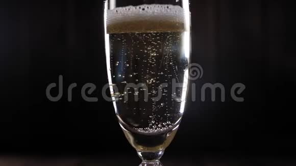 一杯香槟酒的特写镜头黑色背景上有气泡动作缓慢视频的预览图