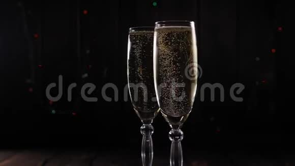 两杯香槟在闪烁的灯光背景上慢慢旋转视频的预览图