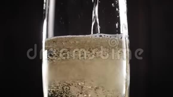 特写的香槟在黑色背景上倒入一个玻璃杯中动作缓慢视频的预览图