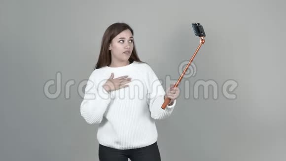 白种人女孩拿着一根自拍棒在感情上说话手势笑视频的预览图