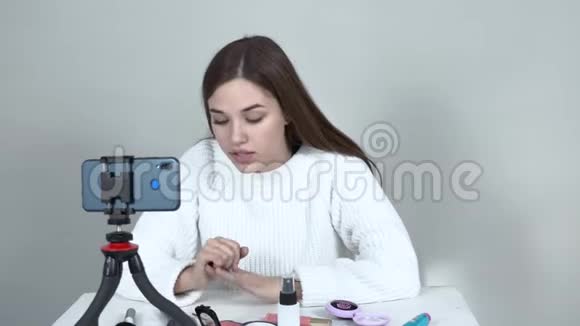 在手机前的白人女孩博主把化妆品放在手上视频的预览图
