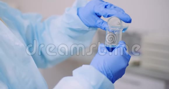 女科学家手里拿着管子和瓶子手里拿着液体视频的预览图