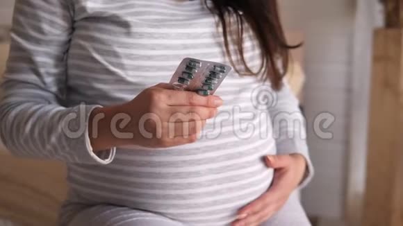 一名孕妇拿着带药丸的水泡的特写镜头视频的预览图