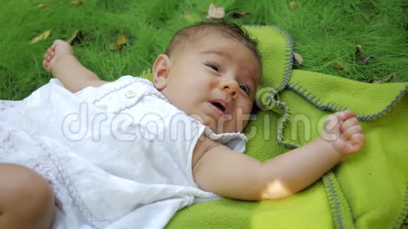 可爱的婴儿宝宝在慢动作中大声打喷嚏两次特写镜头梦幻般的新生婴儿躺在草地上视频的预览图