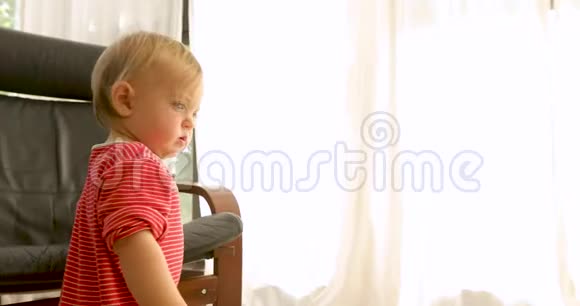 可爱的婴儿站在扶手椅上视频的预览图