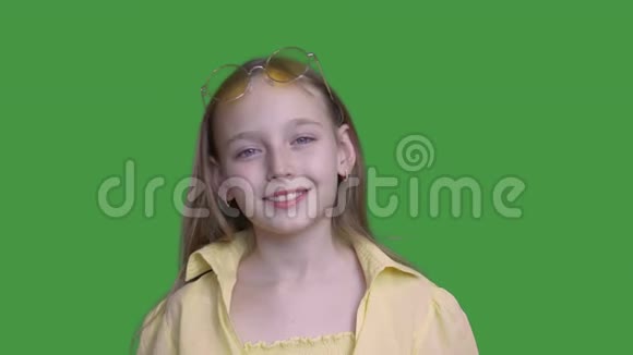 戴太阳镜的女孩在绿色背景下对着镜头微笑视频的预览图