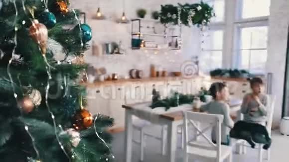 从圣诞树后面看厨房里的孩子们视频的预览图