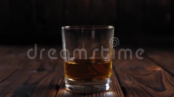 在木制背景上一堆冰块掉进一杯威士忌里视频的预览图