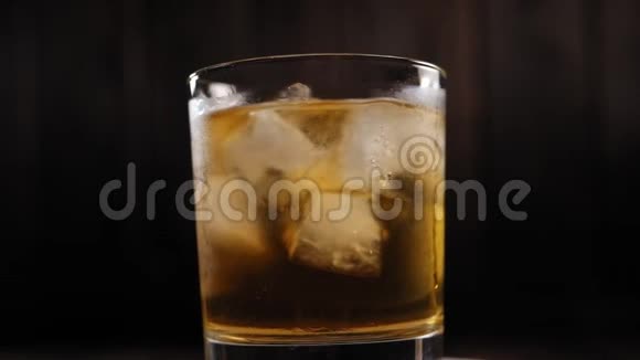 在黑暗的背景下一杯加冰的雾蒙蒙的威士忌酒起来视频的预览图