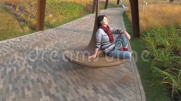 坐在公园长椅上的白人女人闭上了眼睛视频的预览图