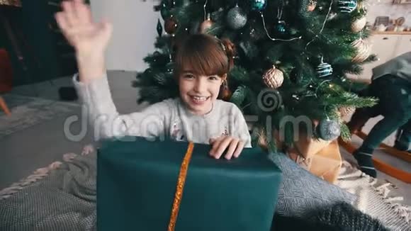 快乐的小女孩在圣诞树旁挥舞着手视频的预览图