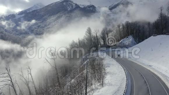 无人机视觉suv汽车在冬季山区蜿蜒的道路上行驶雪山峰和森林上的冬季蛇形道路视频的预览图