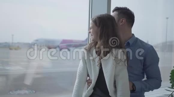 一个漂亮的白人女孩的特写卷发看着飞机起飞与她的父亲坐着的男人视频的预览图