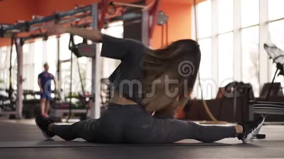 一个运动苗条的女人肌肉背部的足她练习健身坐在一个现代的运动健身房她是视频的预览图