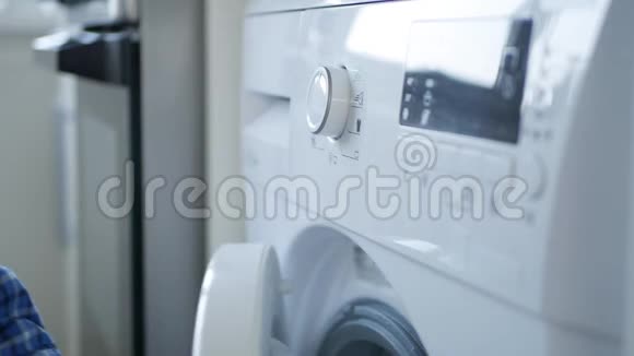 男士关闭洗衣机前门设置程序并按下启动按钮视频的预览图