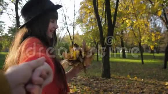 跟我来吧戴帽子的年轻风趣的女人在秋天的秋天散步时欢快地跑着牵着朋友的手视频的预览图