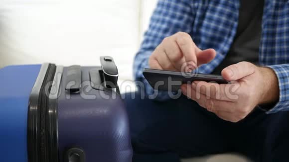 使用移动电话在假日文本中旅行的人手持智能手机的人在手提箱附近等候视频的预览图