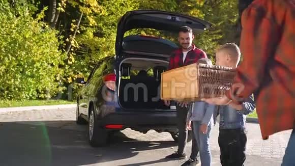 两个可爱的快乐孩子的迷人肖像他们在搬进新车时帮助父母后备箱装载视频的预览图