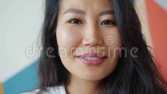 一位迷人的亚洲女士在彩色背景下独自微笑的特写肖像视频的预览图