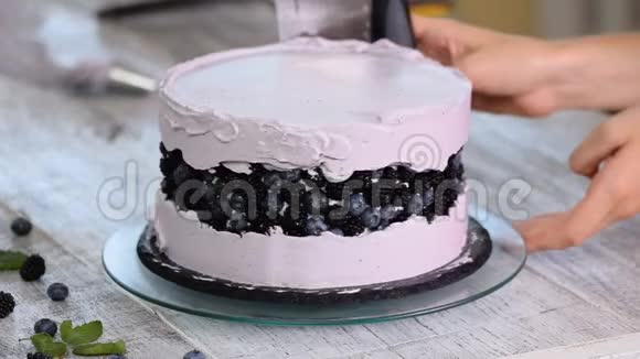 甜点在饼干蛋糕上涂上紫色奶油并用烹饪铲子自制糕点烹饪的概念视频的预览图