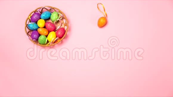 彩色复活节彩蛋在粉红色背景下从篮子中跳跃平躺俯视停止运动视频的预览图