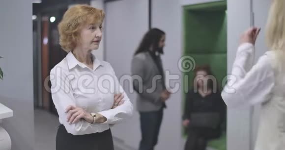 白种人严肃的中年妇女的肖像双手交叉站在空地办公室转向接待处视频的预览图