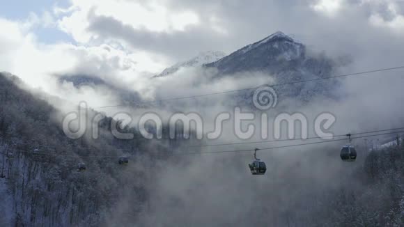 在冬季度假胜地的雾状林地上可以看到滑雪缆车在雪间运送运动员的空中景观滑雪电梯视频的预览图