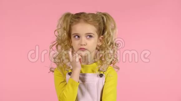 梳着两条马尾辫的金发女郎集中精力思考用手指触摸她的脸视频的预览图