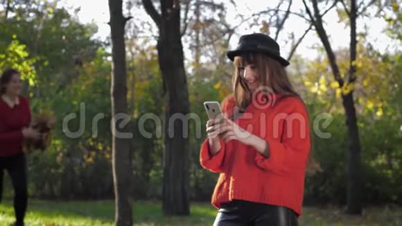 快乐的女朋友可爱的年轻女朋友在秋天的落叶背景下自拍视频的预览图