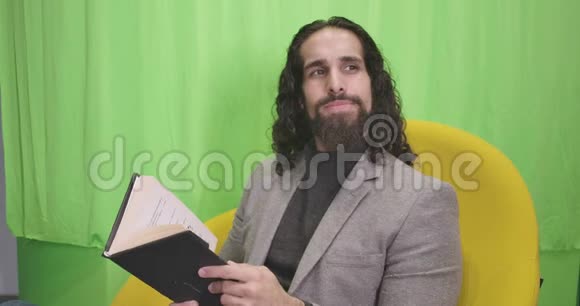 英俊的留胡子中东男人坐着书和思考的肖像穿正装的年轻人揉眼睛视频的预览图